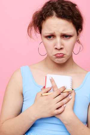 portrait of a woman in a blue T-shirt with a red notepad and a pen of emotions close-up unalteredの写真素材