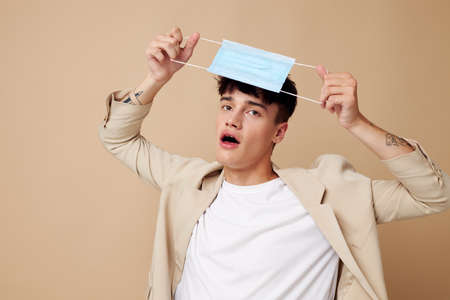 handsome guy in a medical mask in the hands of posing fashion light background unalteredの写真素材