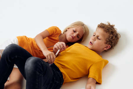 Cute stylish kids lie on the floor with notepads and pencils childhood lifestyle unaltered