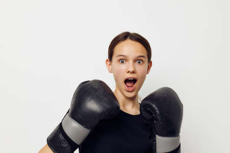 young woman in black sports uniform boxing gloves posing isolated background