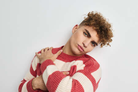 Attractive man in a striped sweater posing light backgroundの写真素材