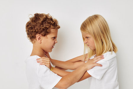 Photo of two children in white T-shirts are standing next to beige backgroundの写真素材