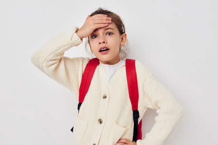 little schoolgirl with red backpack posing isolated background