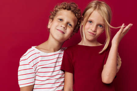 Small children emotions stand side by side in everyday clothes red background unalteredの写真素材
