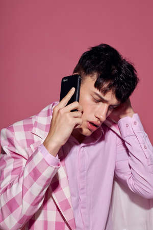 handsome guy with a phone in hand pink blazer fashion elegant style model studioの写真素材