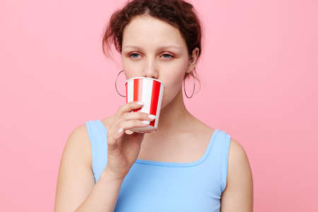 emotional woman from disposable glasses drink pink backgroundの写真素材