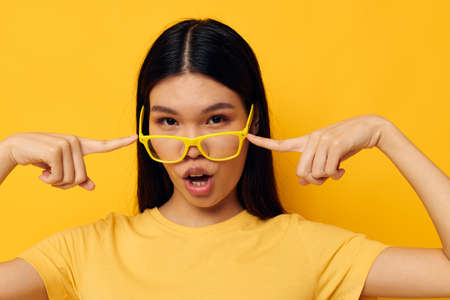 pretty brunette in glasses gesturing with hands copy-space yellow background unaltered