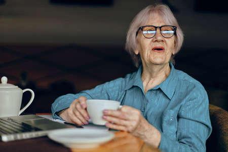 Senior woman in a cafe a cup of drink laptop Retired woman chatting unalteredの写真素材