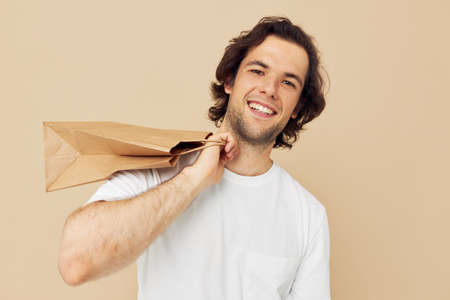 handsome man in a white T-shirt with paper bag Lifestyle unalteredの写真素材