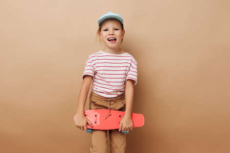 pretty young girl skateboard in hand posing baby clothes fun isolated backgroundの写真素材