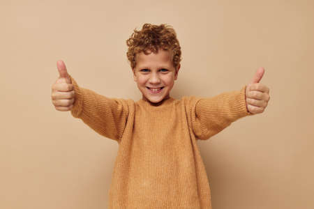 Cute little boy in a beige sweater posing fun childhood unaltered