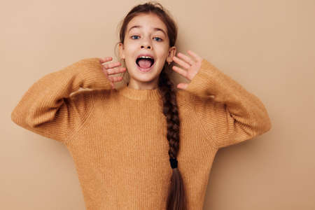 pretty young girl long pigtail beige sweater grimace Lifestyle unalteredの写真素材