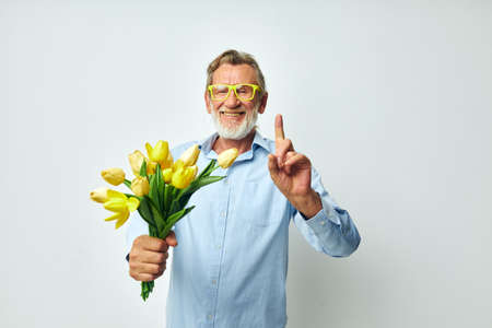 old man a bouquet of flowers with glasses as a gift light background