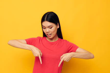 Charming young Asian woman gestures with her hands in casual clothes copy-space yellow background unalteredの写真素材