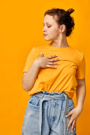pretty girl gestures with hands grimace emotions yellow background unalteredの写真素材