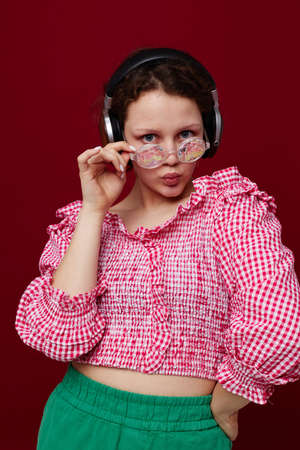 woman wearing headphones glasses with diamond fashion posing red background