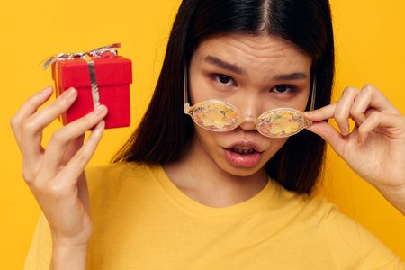 Charming young Asian woman with gift boxes in hands fun posing isolated background unaltered