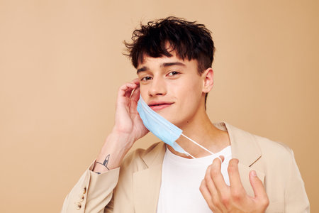 A young man protective mask in hand in hand modern style light background unalteredの写真素材