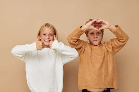 Photo of two children standing next to posing emotions isolated backgroundの写真素材