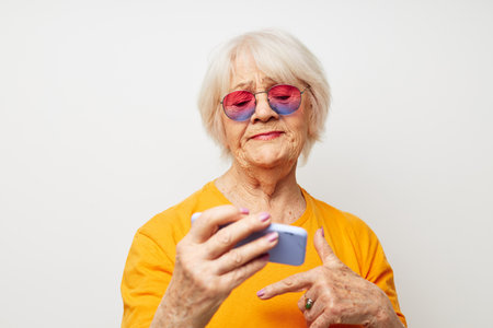 Photo of retired old lady in fashionable glasses with a smartphone in hand cropped viewの写真素材