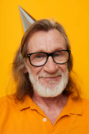 cheerful elderly man in glasses with a cap on his head yellow backgroundの写真素材