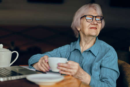 Portrait of an elderly woman working in front of laptop monitor sitting Freelancer works unaltered