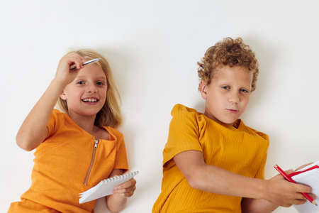 Cute stylish kids lie on the floor with notepads and pencils childhood lifestyle unalteredの写真素材
