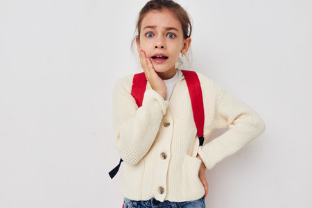 cute schoolgirl with red backpack posing isolated background