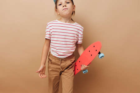 little girl skateboard in hand posing baby clothes fun isolated backgroundの写真素材