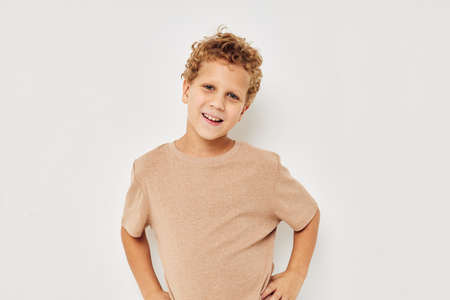 Cheerful boy in beige T-shirt emotions posing light backgroundの写真素材