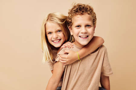 Boy and girl in beige t-shirts posing for fun childhood unalteredの写真素材