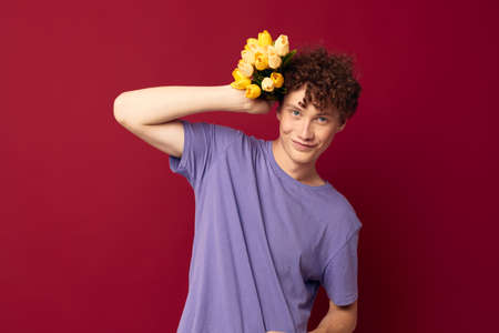 cute teen holding a yellow bouquet of flowers purple t-shirts isolated background unalteredの写真素材