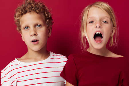 Cute preschool kids emotions stand side by side in everyday clothes red backgroundの写真素材
