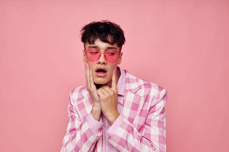 portrait of a young man fashionable pink sunglasses jacket posing pink background unalteredの写真素材