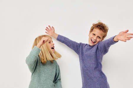 Cute stylish children in multi-colored sweaters posing for fun light backgroundの写真素材