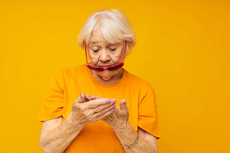 Photo of retired old lady in dark glasses in the shape of a heart yellow backgroundの写真素材