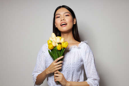 Portrait Asian beautiful young woman in a white shirt flowers spring posing light background unalteredの写真素材