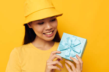 woman with Asian appearance in a yellow T-shirt and a hat with a gift yellow background unalteredの写真素材