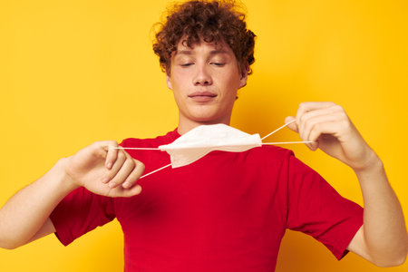 guy with red curly hair in protective masks safety posing yellow background unalteredの写真素材