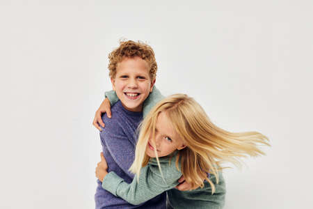 Photo of two children in multi-colored sweaters posing for fun childhood unalteredの写真素材