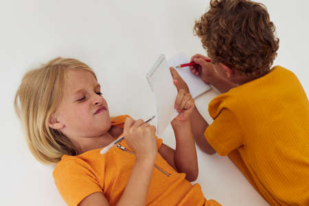 picture of positive boy and girl drawing in notebooks lying on the floor light background unalteredの写真素材