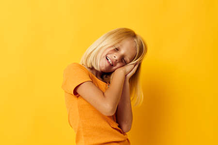 kid girl in a yellow t-shirt smile posing studio color background unalteredの写真素材