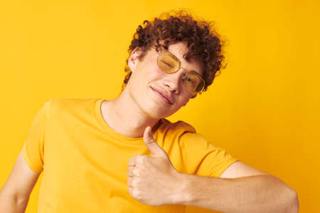 cute red-haired guy yellow t-shirt glasses fashion hand gestures isolated background unalteredの写真素材