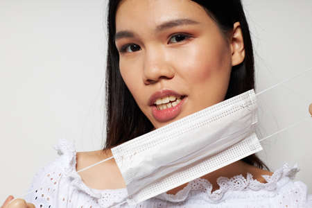 Portrait Asian beautiful young woman medical mask on the head protection light background unalteredの写真素材