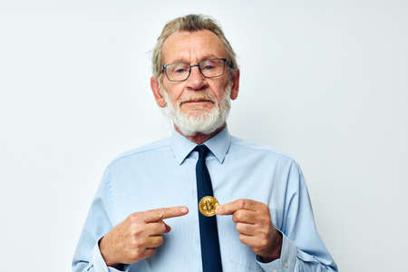 Portrait elderly man Bitcoin cryptocurrency in the hands of a financier isolated backgroundの写真素材