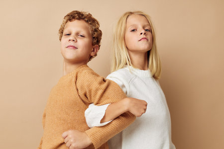 Boy and girl standing next to posing emotions beige backgroundの写真素材