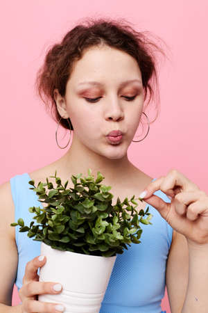 pretty woman flower in white pot posing emotion pink background unalteredの写真素材