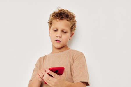 cute boy with curly hair holding a red phone light backgroundの写真素材