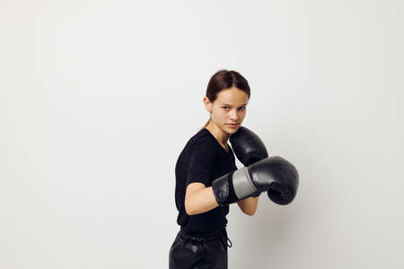 young woman in black sports uniform boxing gloves posing isolated backgroundの写真素材