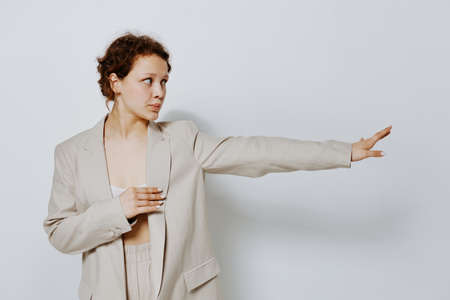 pretty woman In a light classic suit hand gesture light background unalteredの写真素材